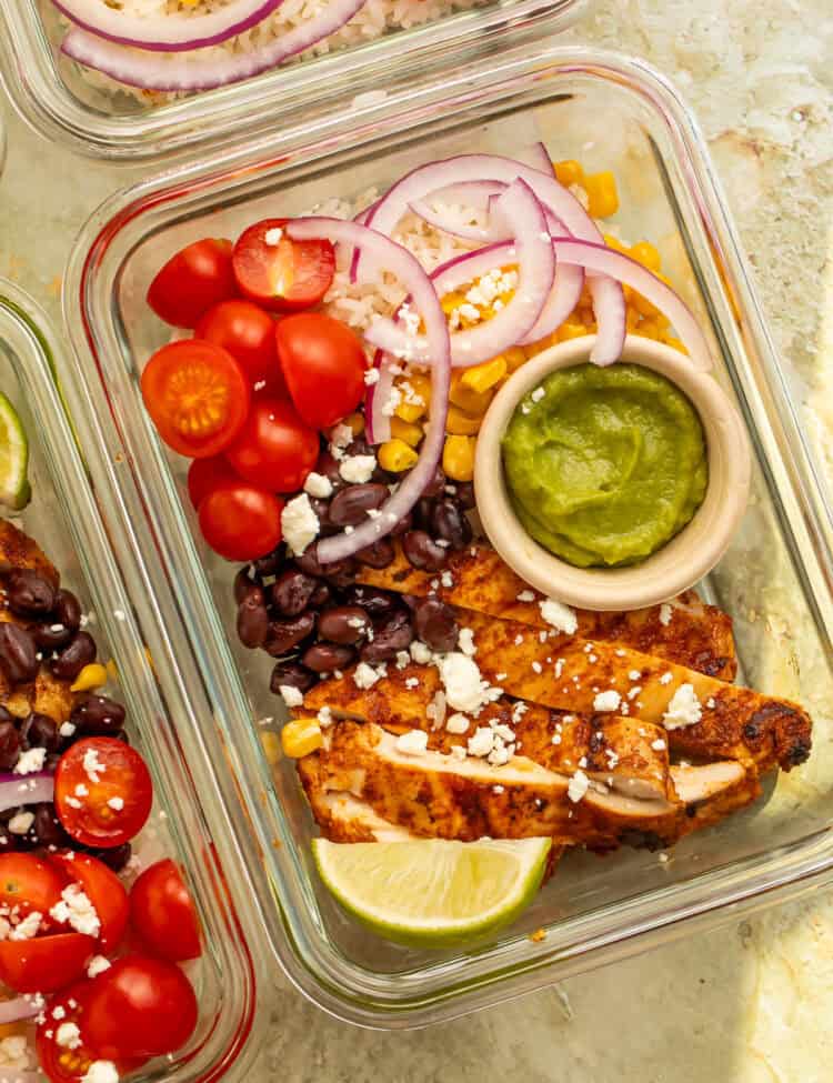 Mexican chicken bowl with sliced grilled chicken, black beans, rice, guacamole, and crumbled feta.