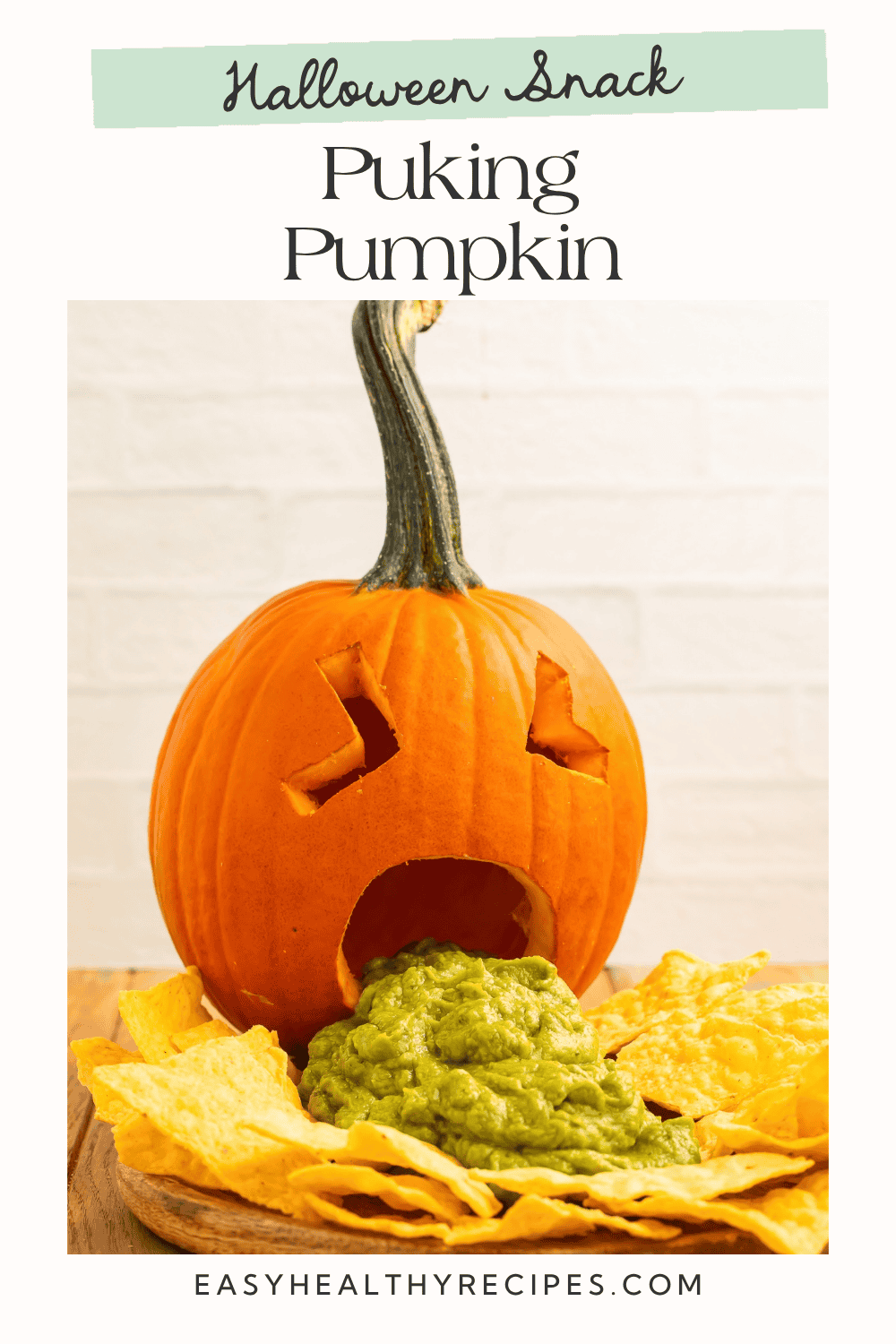 Carved puking pumpkin with guacamole spilling onto a board surrounded by tortilla chips
