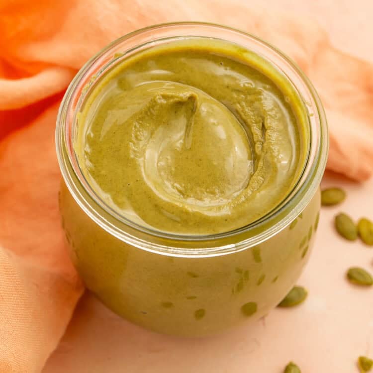 Creamy homemade pumpkin seed butter in a glass jar with scattered pepitas