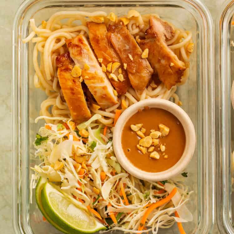 Thai peanut chicken meal prep bowl with rice noodles, cabbage slaw, peanut sauce, peanuts, and lime.