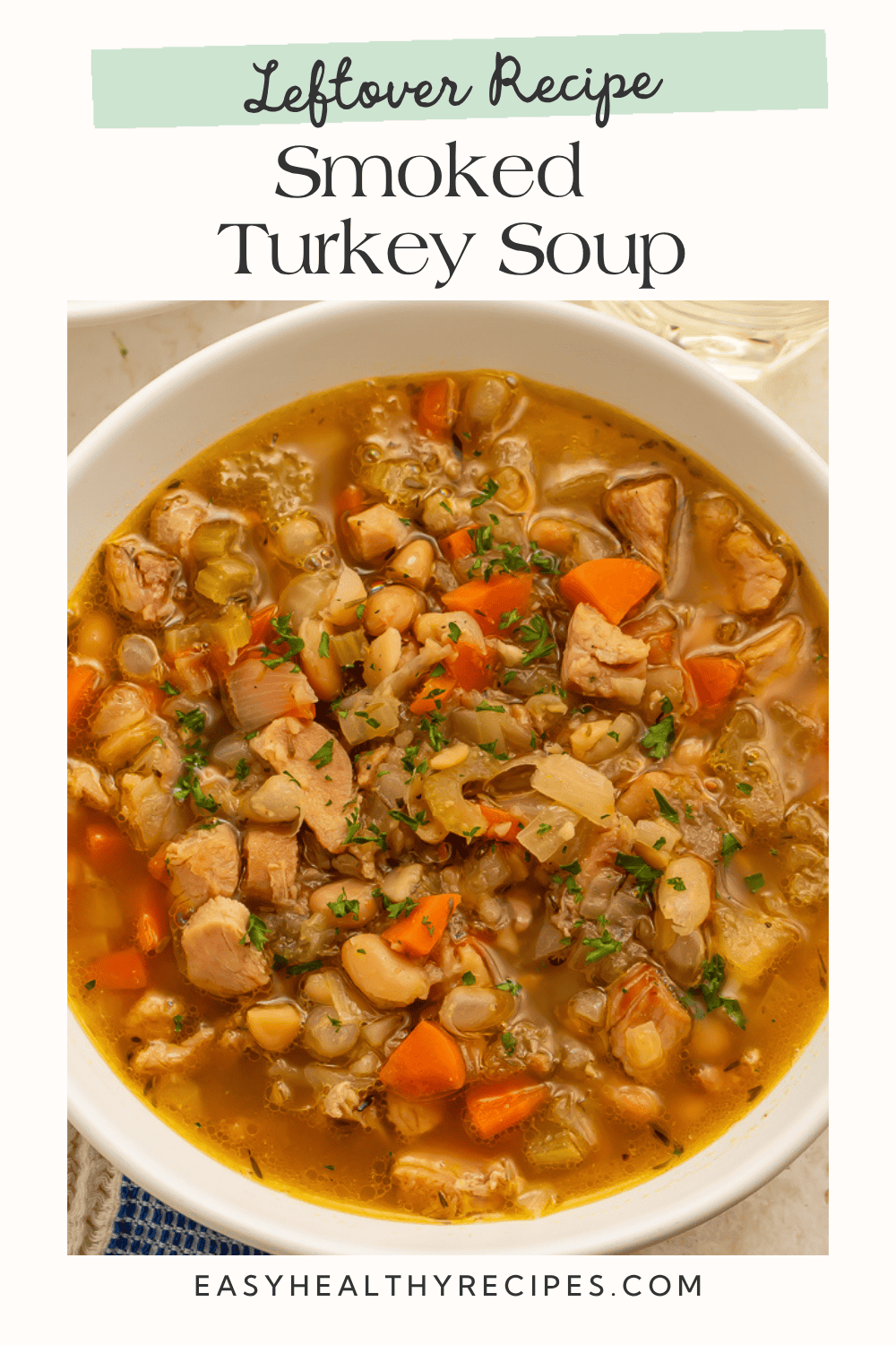 Close up of smoked turkey soup with white beans, carrots, onions, and herbs. Text reads “Leftover Recipe Smoked Turkey Soup."